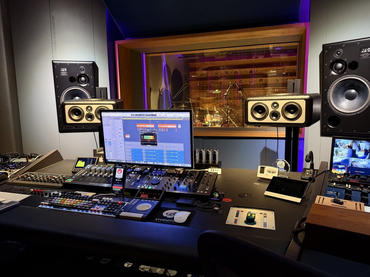A recording studio control room with Logic on screen, dBaton CUE streaming and a phone on the desk